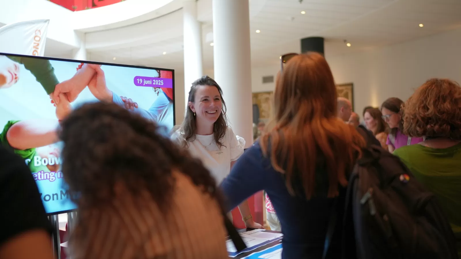 Een medewerker van GGDrU verwelkomt bezoekers van het kennisatelier in Hotel Theater Figi in Zeist.